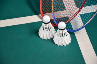 Beyaz kremalı badminton mekik ve raketler kapalı badminton kortunda, yumuşak ve seçici odak mekikleri, kopyalama alanı, dayanıklılık ve ağırlık konseptini gevşetmek için eğlence sporu.