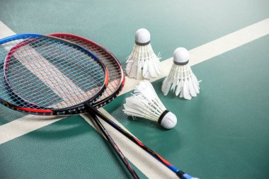 Badminton raketleri ve beyaz kremalı badminton mekikleri oynadıktan sonra ya da yeşil zeminde, kapalı badminton kortunda oynadıktan sonra, dünya çapında badminton severler için yumuşak bir odak, konsept.
