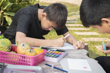 İki çocuk boş zamanlarını çizim, çizim ve boyamakla geçiriyor. Evlerinin arka bahçesinde suluboya boya kullanıyorlar. Gençler yaz konseptinde faaliyet gösteriyor..