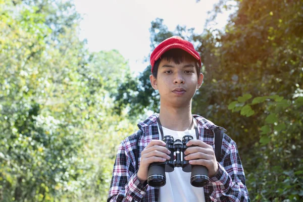 年轻的亚洲男孩 头戴红帽子 身穿格子呢衬衫 手握望远镜 站在那里观看身后的鸟类 森林动物和其他昆虫 这是青少年活动的概念 — 图库照片