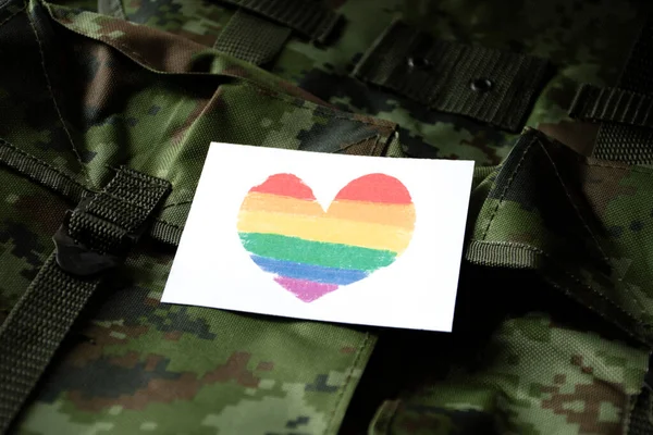迷彩柄のミリタリーバックパックに虹色のカードをハートで描く 人間の性別多様性を尊重し 誇りを持ってLgbtq を祝うためにすべての人々を支援し 呼び出すためのコンセプト — ストック写真