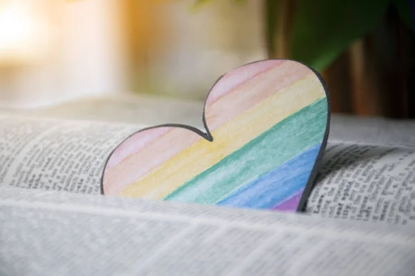 用彩虹色勾画出的心形书签的装帧视图 模糊了翻开的旧书的背景 呼吁所有人在骄傲的一个月里尊重人类的性别多样性 — 图库照片