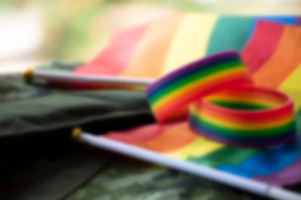 在伪装背景下的彩虹旗和彩虹腕带的模糊图像 世界各国庆祝男女同性恋 双性恋和变性者骄傲月的概念 — 图库照片