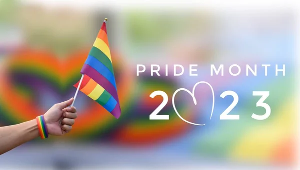 \'Pride Month 2023\' on blurred rainbow flag and wristband background, concept for lgbtq+ people celebrations in pride month, June, around the world and calling out people to respect gender diversity.