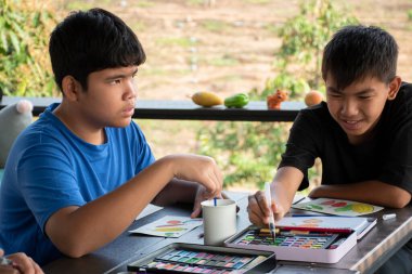 Asyalı çocuklar boş zamanlarını vakalarda suluboya barlar, yazın gençlerin aktiviteleri ve suluboya resim dersleri konsepti kullanarak çizim, resim ve boyama yaparak geçiriyorlar..