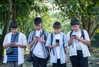 Okuldan sonra birlikte eve yürürken cep telefonu kullanan Asyalı genç çocuklar, gençlerin yaşam tarzı, çocukluk ve gençlerin zaman geçirme konsepti..