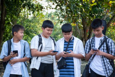 Okuldan sonra birlikte eve yürürken cep telefonu kullanan Asyalı genç çocuklar, gençlerin yaşam tarzı, çocukluk ve gençlerin zaman geçirme konsepti..