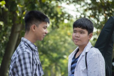 Asyalı genç gay oğlanlar birbirlerini selamlıyor. Hafta sonu Asya 'da okula giderken birbirlerine sevgilerini gösteriyorlar. Yumuşak ve seçici bir odak noktası var..