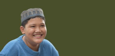 Genç Asyalı Müslüman ya da İslamcı çocuk, beyaz arka planda izole edilmiş, içinde Kuran ve tespih bulunan şapka ve gözlük takıyor.. 