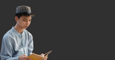 Genç Asyalı Müslüman ya da İslamcı çocuk, beyaz arka planda izole edilmiş, içinde Kuran ve tespih bulunan şapka ve gözlük takıyor.. 