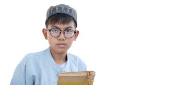 Genç Asyalı Müslüman ya da İslamcı çocuk, beyaz arka planda izole edilmiş, içinde Kuran ve tespih bulunan şapka ve gözlük takıyor.. 