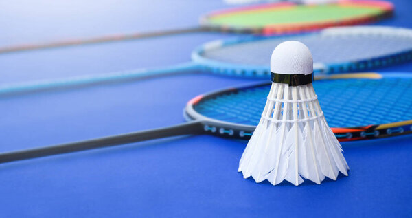 Closeup image of badminton shuttlecocks on rackets with blurred indoor badminton court background, soft and selective focus on front shuttlecock, concept for healthy and favorite indoor sports.