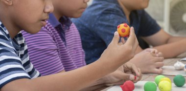Asyalı çocuklar birlikte oturur ve plastik kalıpları kullanarak öğrenirler. Soldaki çocuğa odaklanırlar. Dünyanın dört bir yanındaki çocukların boş zaman ve hobi aktivitelerine odaklanırlar..