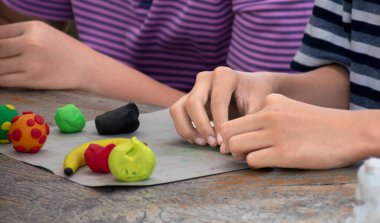Asyalı çocuklar birlikte oturur ve plastik kalıpları kullanarak öğrenirler. Soldaki çocuğa odaklanırlar. Dünyanın dört bir yanındaki çocukların boş zaman ve hobi aktivitelerine odaklanırlar..