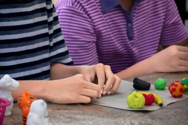 Asyalı çocuklar birlikte oturur ve plastik kalıpları kullanarak öğrenirler. Soldaki çocuğa odaklanırlar. Dünyanın dört bir yanındaki çocukların boş zaman ve hobi aktivitelerine odaklanırlar..