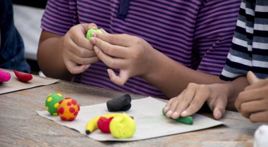 Asyalı çocuklar birlikte oturur ve plastik kalıpları kullanarak öğrenirler. Soldaki çocuğa odaklanırlar. Dünyanın dört bir yanındaki çocukların boş zaman ve hobi aktivitelerine odaklanırlar..