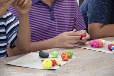 Asyalı çocuklar birlikte oturur ve plastik kalıpları kullanarak öğrenirler. Soldaki çocuğa odaklanırlar. Dünyanın dört bir yanındaki çocukların boş zaman ve hobi aktivitelerine odaklanırlar..