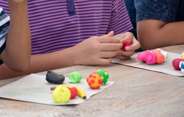 Asyalı çocuklar birlikte oturur ve plastik kalıpları kullanarak öğrenirler. Soldaki çocuğa odaklanırlar. Dünyanın dört bir yanındaki çocukların boş zaman ve hobi aktivitelerine odaklanırlar..