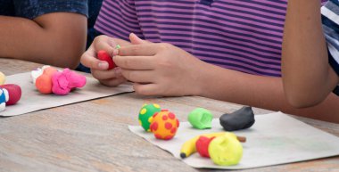 Asyalı çocuklar birlikte oturur ve plastik kalıpları kullanarak öğrenirler. Soldaki çocuğa odaklanırlar. Dünyanın dört bir yanındaki çocukların boş zaman ve hobi aktivitelerine odaklanırlar..