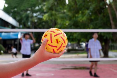 Sepaktakham topu, okuldan sonra birlikte oynayan öğrencinin elinde, yumuşak ve seçici bir odaklanma..