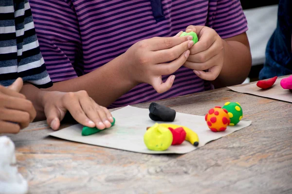 Asyalı çocuklar birlikte oturur ve plastik kalıpları kullanarak öğrenirler. Soldaki çocuğa odaklanırlar. Dünyanın dört bir yanındaki çocukların boş zaman ve hobi aktivitelerine odaklanırlar..