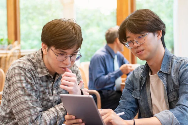 Portrait of young adult businessmen are talking and consulting their digital nomad problems in coffee shop, digital nomad of teenagers lifestyle concept.