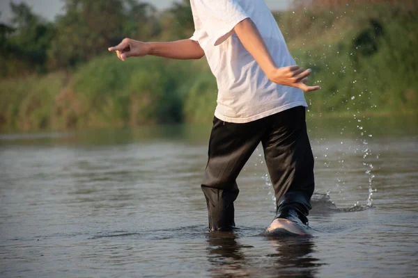 在课余时间 亚洲男孩在当地的河边扔石头 在世界各地 他在课余时间 在运动中 在儿童业余爱好的概念和童年 — 图库照片