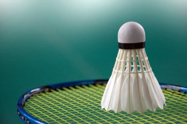 Badminton raketleri ve beyaz kremalı badminton mekikleri yeşil zeminde, badminton kortunda, yumuşak odak, dünyadaki badminton severler için konsept.