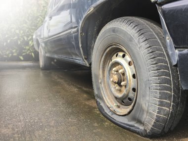 Eski kamyonetin siyah tekerleği düz ve çimento zemine park edilmiş, yeni bir tane değiştirmek için bekliyor, araba bakım ve araba sigortası konsepti..