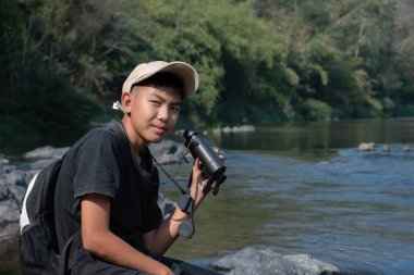 Asisn yakışıklı çocuk dürbünü tutuyor ve yerel ulusal parktaki kuş izleme etkinliğine katılıyor, yeni düzenlenmiş, dünyanın dört bir yanındaki gençlerin doğa ve çevre çalışmaları konsepti..