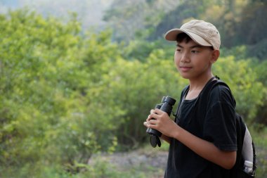 Asisn yakışıklı çocuk dürbünü tutuyor ve yerel ulusal parktaki kuş izleme etkinliğine katılıyor, yeni düzenlenmiş, dünyanın dört bir yanındaki gençlerin doğa ve çevre çalışmaları konsepti..