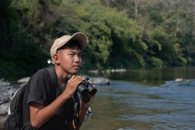 Asisn yakışıklı çocuk dürbünü tutuyor ve yerel ulusal parktaki kuş izleme etkinliğine katılıyor, yeni düzenlenmiş, dünyanın dört bir yanındaki gençlerin doğa ve çevre çalışmaları konsepti..