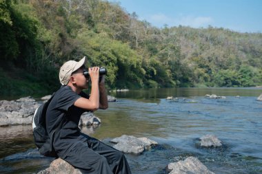 Asisn yakışıklı çocuk dürbünü tutuyor ve yerel ulusal parktaki kuş izleme etkinliğine katılıyor, yeni düzenlenmiş, dünyanın dört bir yanındaki gençlerin doğa ve çevre çalışmaları konsepti..