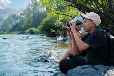 Asisn yakışıklı çocuk dürbünü tutuyor ve yerel ulusal parktaki kuş izleme etkinliğine katılıyor, yeni düzenlenmiş, dünyanın dört bir yanındaki gençlerin doğa ve çevre çalışmaları konsepti..