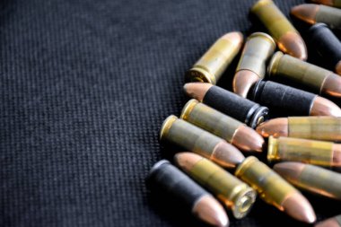 Gri arka planda 9mm 'lik tabanca mermileri, yumuşak odaklanma, yeni düzenleme, spor çekme konsepti ve dünya çapında insan hayatını ve mülkünü korumak için eğitim kavramı.