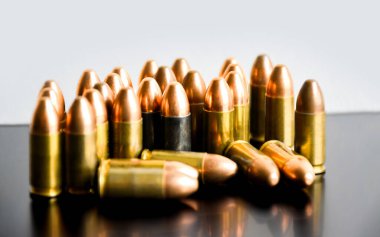 Gri arka planda 9mm 'lik tabanca mermileri, yumuşak odaklanma, yeni düzenleme, spor çekme konsepti ve dünya çapında insan hayatını ve mülkünü korumak için eğitim kavramı.