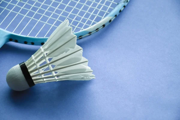 Badminton sport equipments, shuttlecock and racket, on light blue floor, blurred background, endurance sports concept.