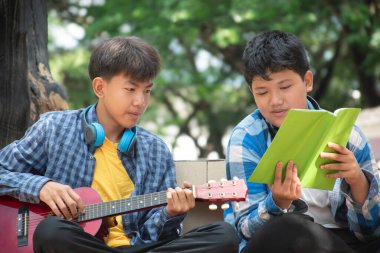 Parkta akustik gitar çalan Asyalı çocuklar, yumuşak ve seçici odaklı..