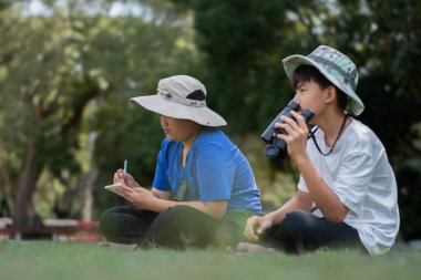 Asyalı öğrenciler boş zamanlarını kuşları, böcekleri, böcekleri ve hayvanları izleyerek geçiriyorlar. Tropikal ormanlarda ağaçların dallarında uçan, sürünen ve tırmanan hayvanlar, soldaki çocuğa yumuşak ve seçici bir şekilde odaklanıyorlar..