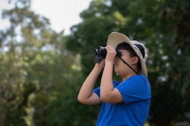 Asyalı öğrenciler boş zamanlarını kuşları, böcekleri, böcekleri ve hayvanları izleyerek geçiriyorlar. Tropikal ormanlarda ağaçların dallarında uçan, sürünen ve tırmanan hayvanlar, soldaki çocuğa yumuşak ve seçici bir şekilde odaklanıyorlar..