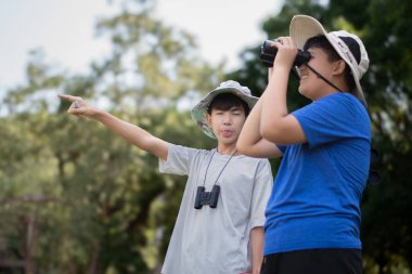 Asyalı öğrenciler boş zamanlarını kuşları, böcekleri, böcekleri ve hayvanları izleyerek geçiriyorlar. Tropikal ormanlarda ağaçların dallarında uçan, sürünen ve tırmanan hayvanlar, soldaki çocuğa yumuşak ve seçici bir şekilde odaklanıyorlar..
