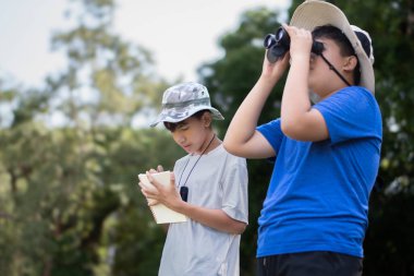 Asyalı öğrenciler boş zamanlarını kuşları, böcekleri, böcekleri ve hayvanları izleyerek geçiriyorlar. Tropikal ormanlarda ağaçların dallarında uçan, sürünen ve tırmanan hayvanlar, soldaki çocuğa yumuşak ve seçici bir şekilde odaklanıyorlar..