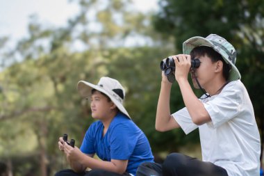 Asyalı öğrenciler boş zamanlarını kuşları, böcekleri, böcekleri ve hayvanları izleyerek geçiriyorlar. Tropikal ormanlarda ağaçların dallarında uçan, sürünen ve tırmanan hayvanlar, soldaki çocuğa yumuşak ve seçici bir şekilde odaklanıyorlar..