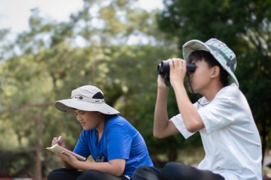 Asyalı öğrenciler boş zamanlarını kuşları, böcekleri, böcekleri ve hayvanları izleyerek geçiriyorlar. Tropikal ormanlarda ağaçların dallarında uçan, sürünen ve tırmanan hayvanlar, soldaki çocuğa yumuşak ve seçici bir şekilde odaklanıyorlar..