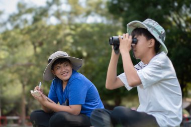 Asyalı öğrenciler boş zamanlarını kuşları, böcekleri, böcekleri ve hayvanları izleyerek geçiriyorlar. Tropikal ormanlarda ağaçların dallarında uçan, sürünen ve tırmanan hayvanlar, soldaki çocuğa yumuşak ve seçici bir şekilde odaklanıyorlar..
