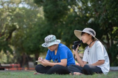Asyalı öğrenciler boş zamanlarını kuşları, böcekleri, böcekleri ve hayvanları izleyerek geçiriyorlar. Tropikal ormanlarda ağaçların dallarında uçan, sürünen ve tırmanan hayvanlar, soldaki çocuğa yumuşak ve seçici bir şekilde odaklanıyorlar..