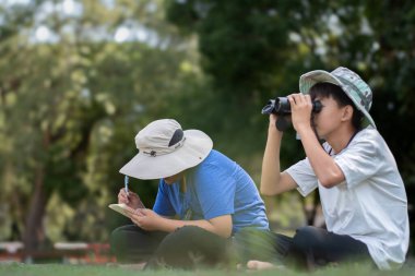 Asyalı öğrenciler boş zamanlarını kuşları, böcekleri, böcekleri ve hayvanları izleyerek geçiriyorlar. Tropikal ormanlarda ağaçların dallarında uçan, sürünen ve tırmanan hayvanlar, soldaki çocuğa yumuşak ve seçici bir şekilde odaklanıyorlar..