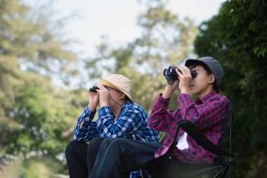 Asyalı öğrenciler boş zamanlarını kuşları, böcekleri, böcekleri ve hayvanları izleyerek geçiriyorlar. Tropikal ormanlarda ağaçların dallarında uçan, sürünen ve tırmanan hayvanlar, soldaki çocuğa yumuşak ve seçici bir şekilde odaklanıyorlar..
