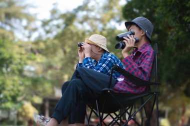 Asyalı öğrenciler boş zamanlarını kuşları, böcekleri, böcekleri ve hayvanları izleyerek geçiriyorlar. Tropikal ormanlarda ağaçların dallarında uçan, sürünen ve tırmanan hayvanlar, soldaki çocuğa yumuşak ve seçici bir şekilde odaklanıyorlar..