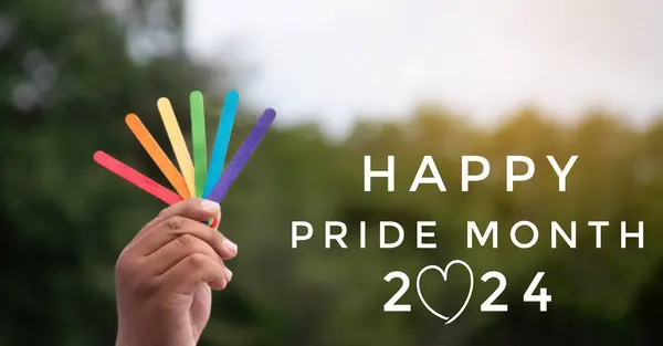 Happy pride month 2024 and hand holding rainbow ice cream sticks on blurred park background, concept for LGBT people celebrations in pride month around the world.